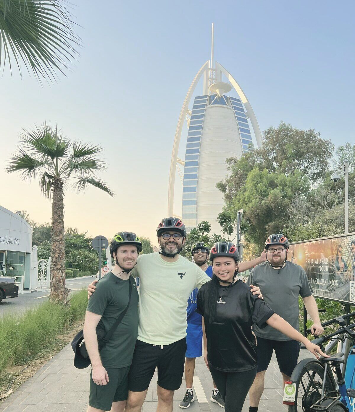 Tom and four teammates in bike helmets, the Burj Al Arab behind them in Dubai.