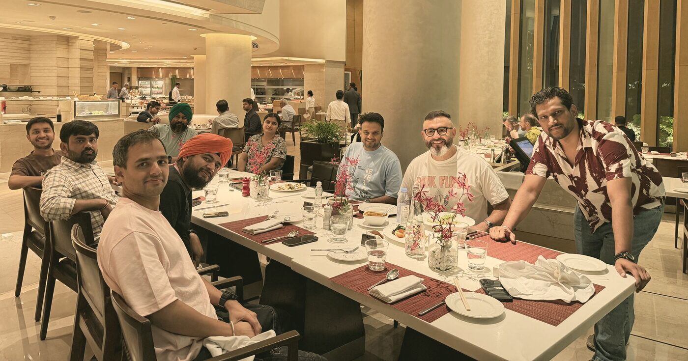 Tom at a long dinner table with former teammates in India.